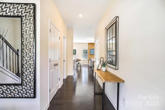 corridor with dark wood-style floors, stairway, and baseboards