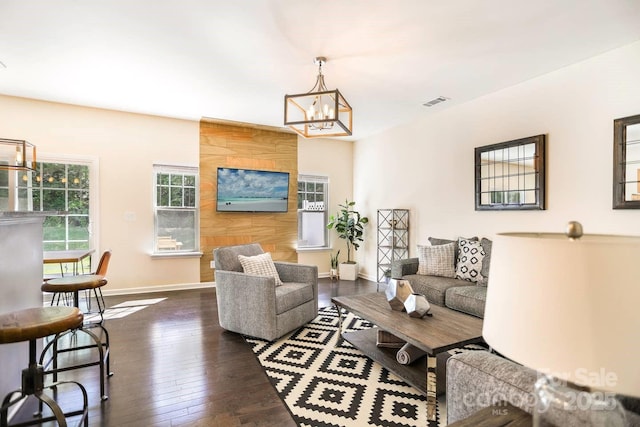 living area with visible vents, baseboards, an inviting chandelier, and dark wood finished floors