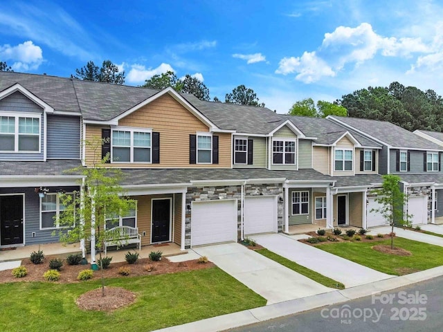 multi unit property featuring covered porch, a garage, stone siding, driveway, and a front lawn