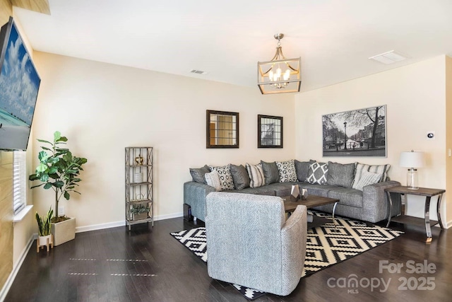 living room with baseboards, wood finished floors, visible vents, and a chandelier