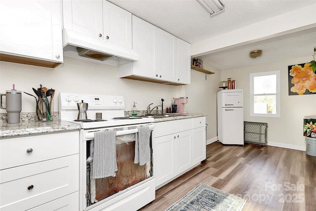 kitchen featuring light wood finished floors, electric range, refrigerator, custom exhaust hood, and white cabinetry