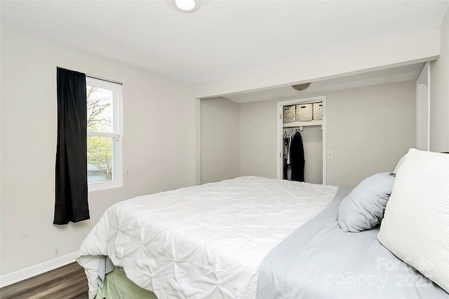 bedroom with a closet, a textured ceiling, baseboards, and wood finished floors