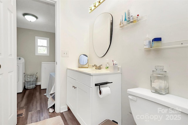 bathroom with independent washer and dryer, vanity, toilet, and wood finished floors