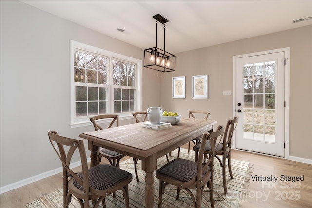 dining area with light wood-style floors, baseboards, and visible vents