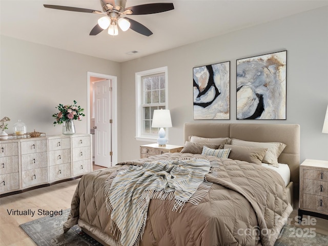 bedroom featuring visible vents, light wood finished floors, and a ceiling fan