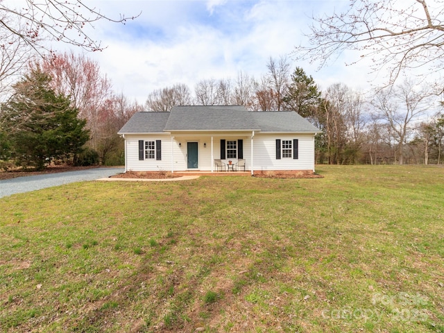 ranch-style house featuring roof with shingles, a porch, and a front yard