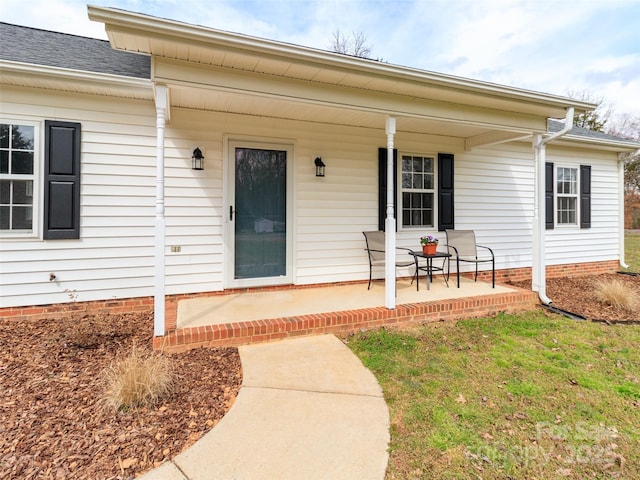 property entrance featuring a porch and roof with shingles