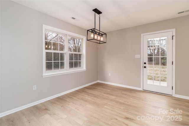 unfurnished dining area featuring light wood finished floors, visible vents, and baseboards