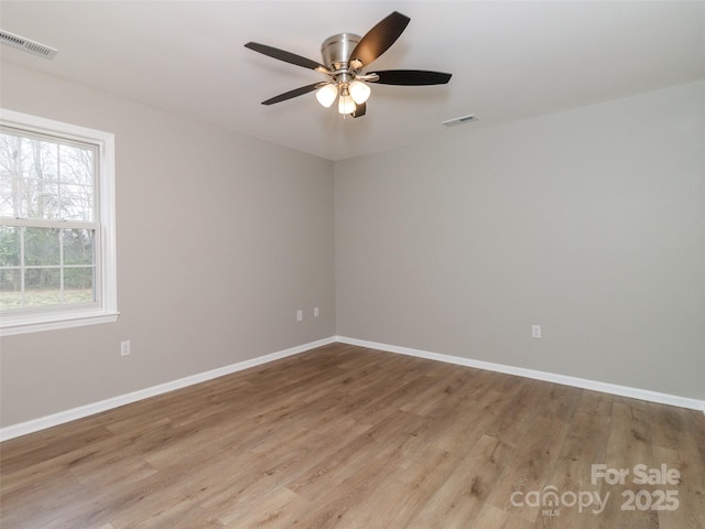 empty room featuring visible vents, light wood-style flooring, and baseboards