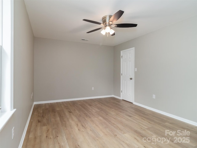 spare room with light wood-type flooring, baseboards, visible vents, and ceiling fan