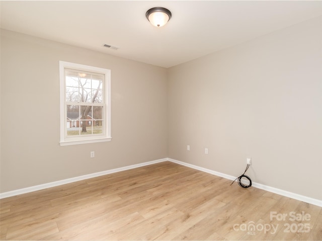 unfurnished room featuring light wood-style floors, visible vents, and baseboards