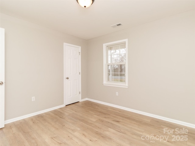 spare room featuring light wood-style flooring, visible vents, and baseboards