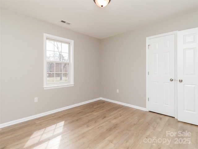 unfurnished bedroom with visible vents, light wood-style flooring, and baseboards