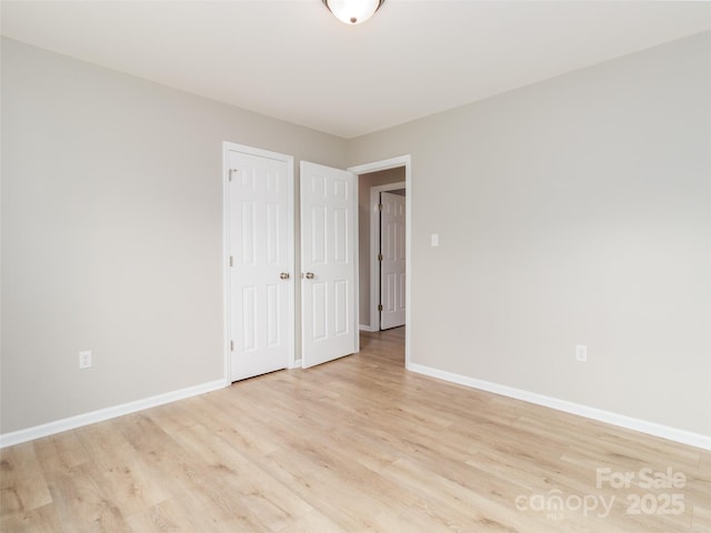 empty room with light wood-style flooring and baseboards