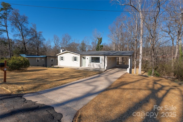 view of front of home with a chimney, stucco siding, concrete driveway, an attached carport, and a front lawn