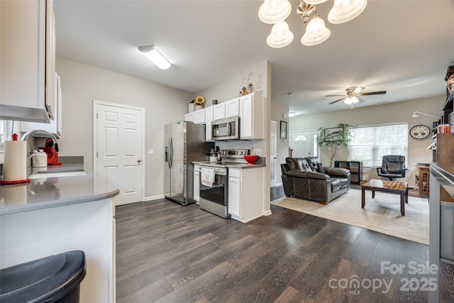 kitchen featuring dark wood-style floors, stainless steel appliances, open floor plan, white cabinetry, and a sink