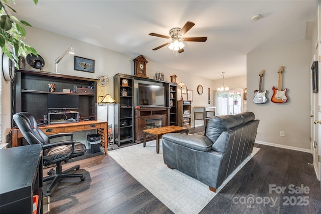 living area with ceiling fan with notable chandelier, wood finished floors, and baseboards