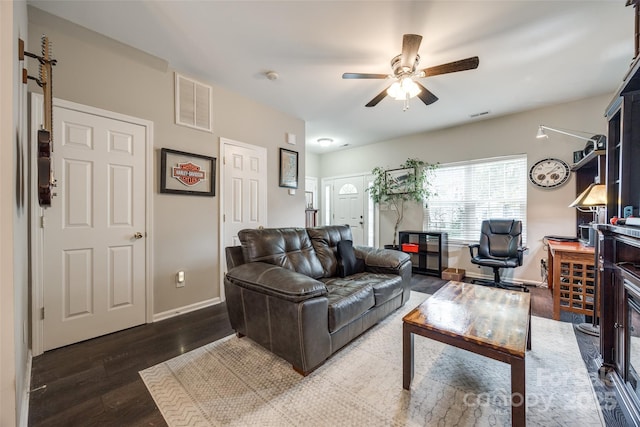 living area with a ceiling fan, visible vents, baseboards, and wood finished floors