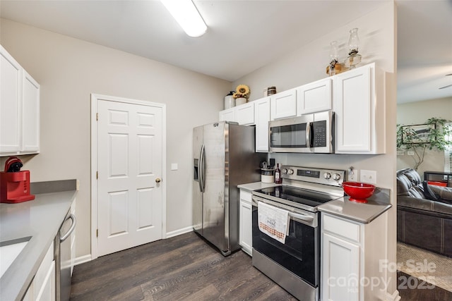 kitchen with dark wood-type flooring, white cabinetry, baseboards, light countertops, and appliances with stainless steel finishes