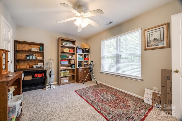 carpeted office space featuring a ceiling fan, visible vents, and baseboards