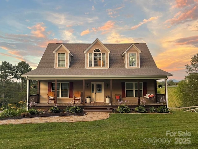 view of front of home with a porch, roof with shingles, and a lawn