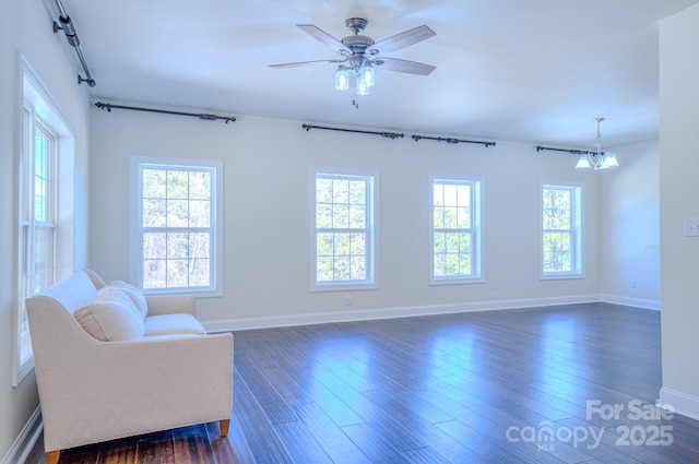 sitting room with dark wood finished floors, baseboards, and ceiling fan with notable chandelier