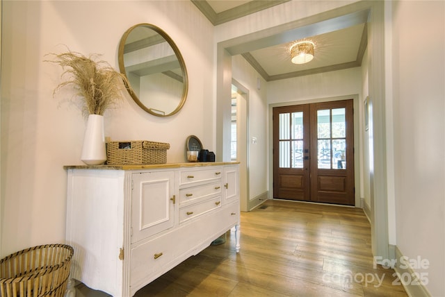 foyer entrance with french doors, crown molding, baseboards, and wood finished floors