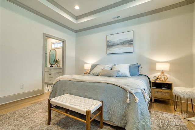 bedroom featuring visible vents, a tray ceiling, wood finished floors, crown molding, and baseboards