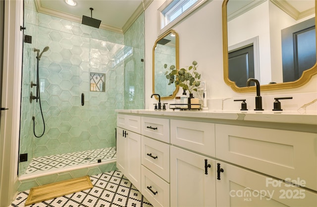 bathroom with a sink, a stall shower, crown molding, and double vanity