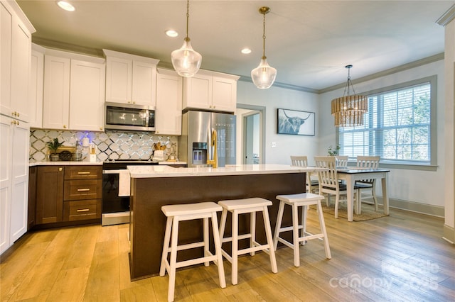 kitchen with a kitchen bar, tasteful backsplash, white cabinetry, appliances with stainless steel finishes, and crown molding