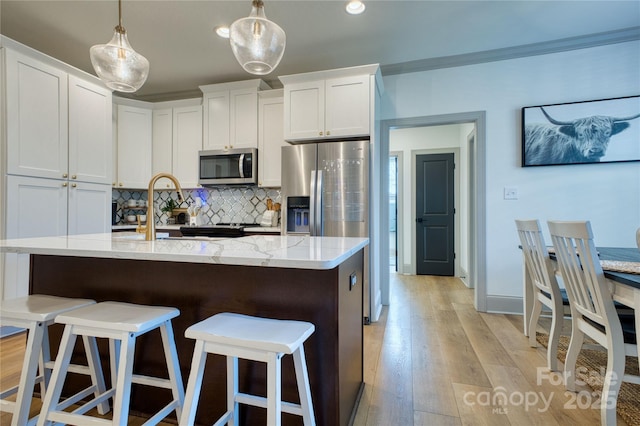 kitchen with tasteful backsplash, a breakfast bar, light wood-type flooring, light stone counters, and stainless steel appliances