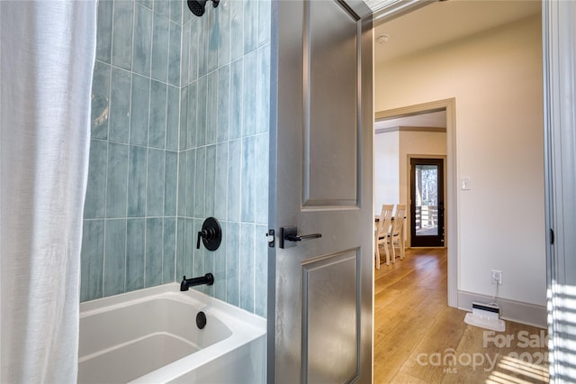 bathroom with wood finished floors, baseboards, and shower / tub combo with curtain