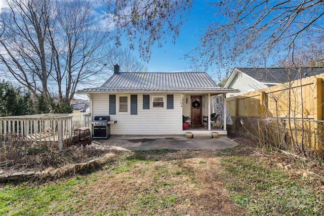 back of house with metal roof and fence