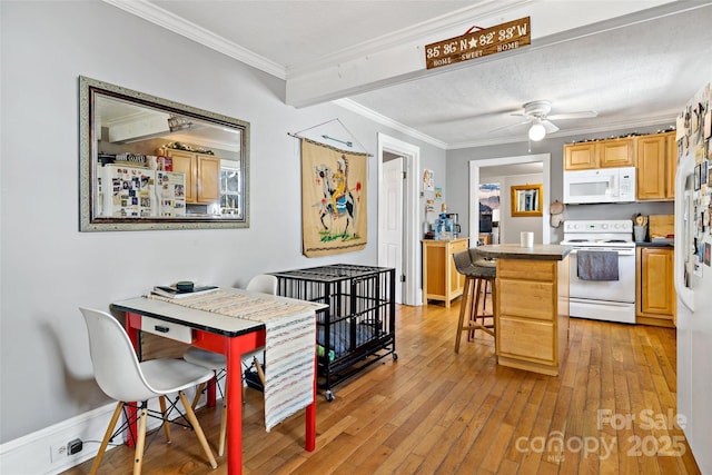 kitchen with crown molding, a breakfast bar, light wood-type flooring, white appliances, and a ceiling fan