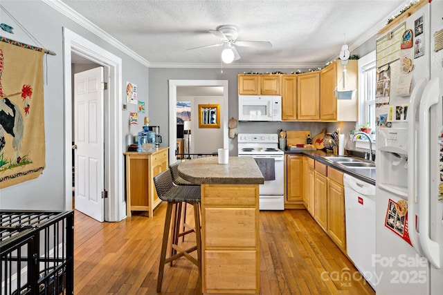 kitchen with a sink, a textured ceiling, white appliances, crown molding, and light wood finished floors