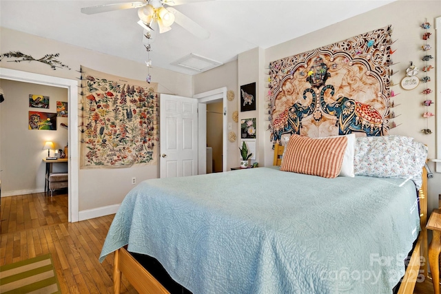 bedroom with ceiling fan, attic access, baseboards, and hardwood / wood-style flooring