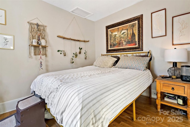 bedroom featuring baseboards, attic access, and wood finished floors