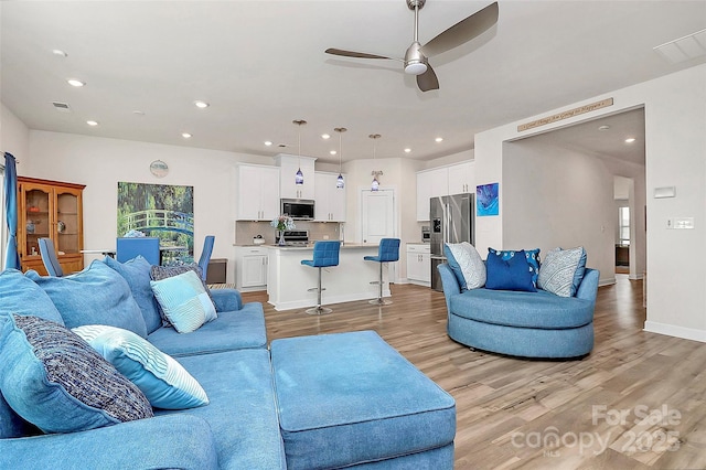 living area with visible vents, baseboards, light wood-style flooring, and recessed lighting