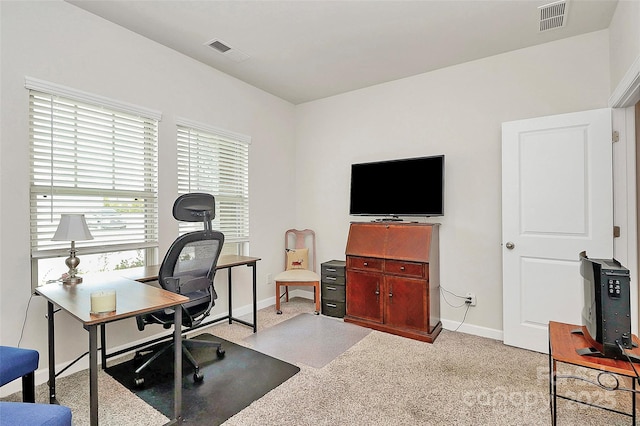 office space featuring baseboards, visible vents, and light colored carpet