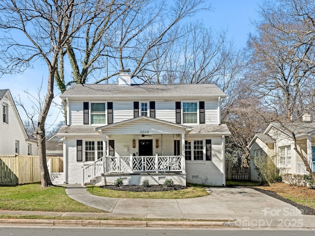 traditional home with a porch, crawl space, brick siding, and fence