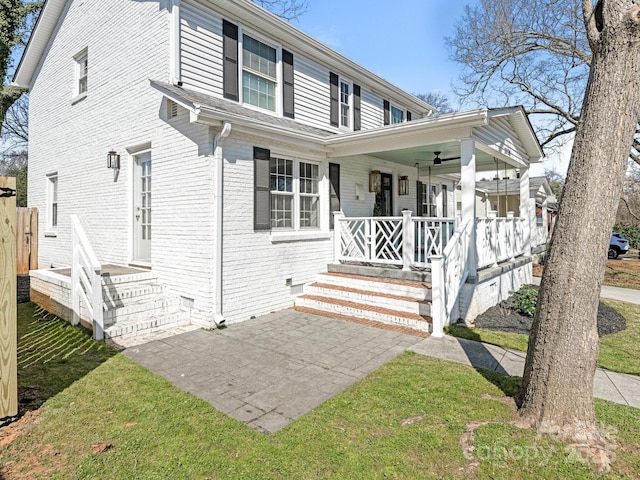 view of front facade with covered porch, ceiling fan, and brick siding