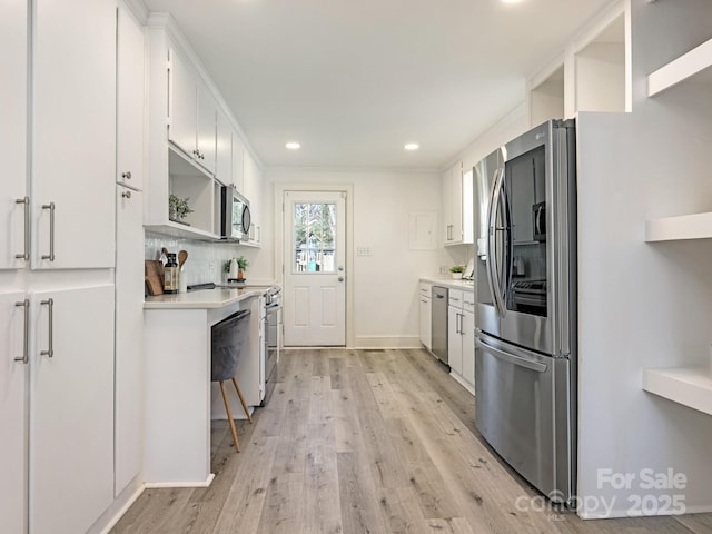 kitchen with light wood finished floors, stainless steel appliances, tasteful backsplash, and light countertops