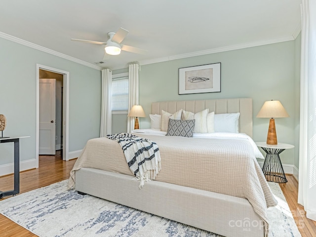 bedroom with a ceiling fan, crown molding, baseboards, and wood finished floors