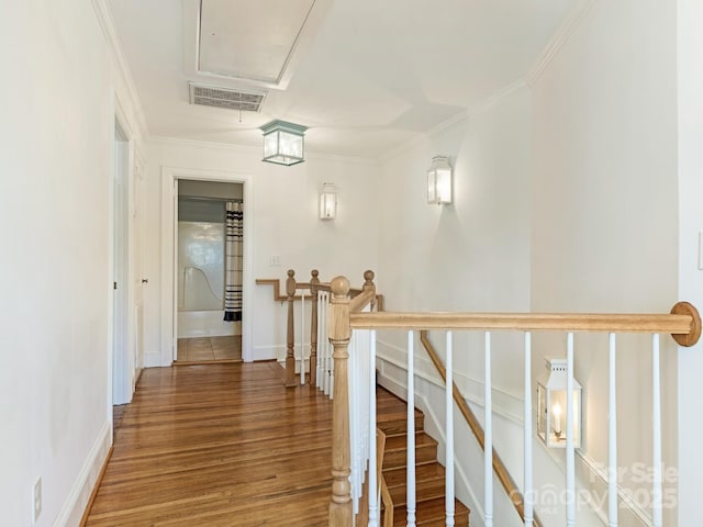 hall with visible vents, attic access, ornamental molding, an upstairs landing, and wood finished floors