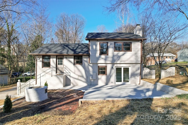 back of house with brick siding, a chimney, a patio area, and fence