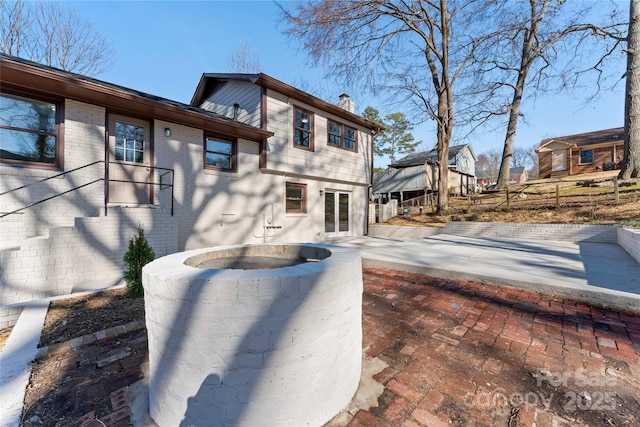 back of property featuring a chimney, a patio, and brick siding