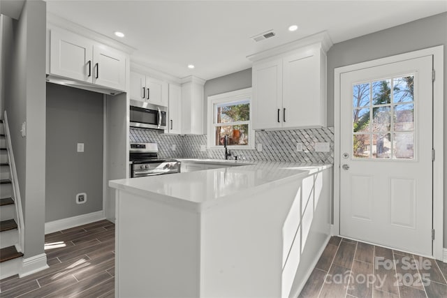 kitchen with stainless steel appliances, a sink, visible vents, and wood tiled floor