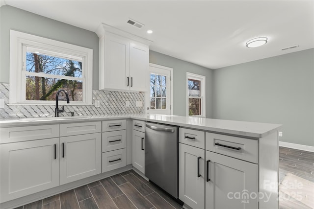 kitchen featuring light countertops, visible vents, stainless steel dishwasher, wood tiled floor, and a peninsula