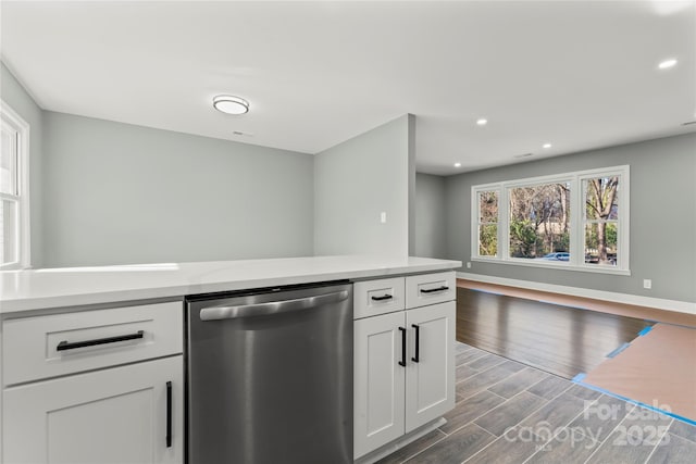 kitchen featuring dark wood-style flooring, white cabinetry, baseboards, light countertops, and dishwasher