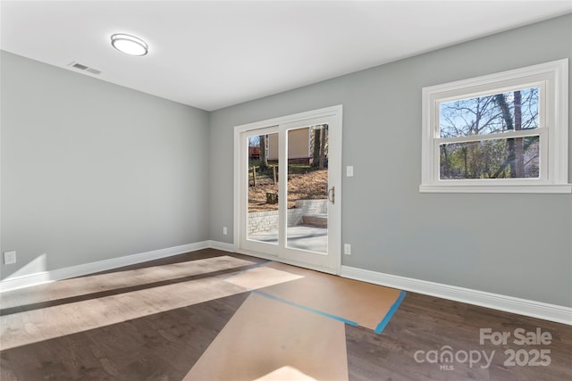 unfurnished room with baseboards, visible vents, and wood finished floors